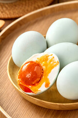 Salted duck eggs, a type of hand-pickled egg, are placed on a wooden table indoors
