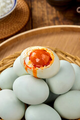 Salted duck eggs, a type of hand-pickled egg, are placed on a wooden table indoors