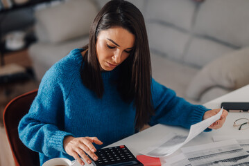 Focused freelancer calculating domestic bills at home office desk