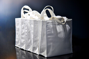 White gift bag with ribbon on black background, close up.