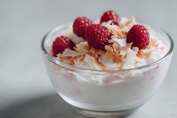 Creamy almond yogurt parfait topped with raspberries and coconut flakes