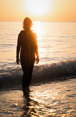 Old oman in wetsuit with surfing board or sup, beach. Senior lady having active lifestyle at sea