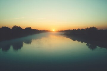Naklejka premium Serene sunrise over a tranquil river surrounded by trees in early morning light