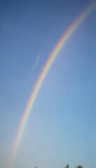 A vibrant arc of rainbow magically appears in a pristine blue sky , celestial, atmospheric
