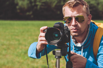 Photographer in sunglasses taking pictures against the backdrop of the landscape.