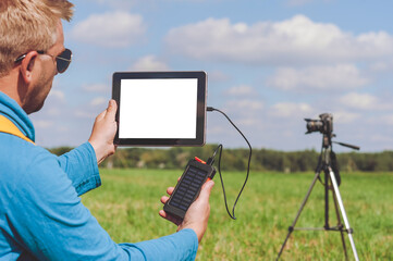 Mockup of a tablet with a charger from a power bank in the hands of a man.