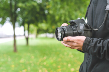 Fototapeta premium Camera in the hands of a man in a beautiful park.