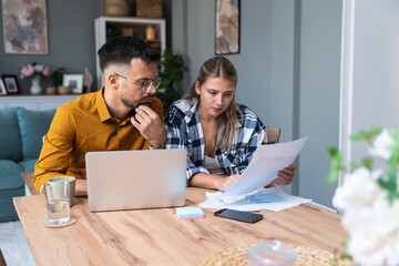 Young intelligent innovative hipster couple presenting their startup new business idea via video call on laptop computer, working at home, talking to potential investor. Modern technology innovation.