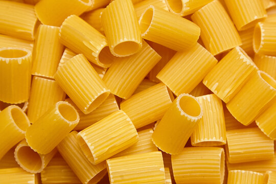 Dry mezzi rigatoni pasta tubes in a detailed close-up view showing ridges, cylindrical shape, and raw texture, ideal for Italian food concepts