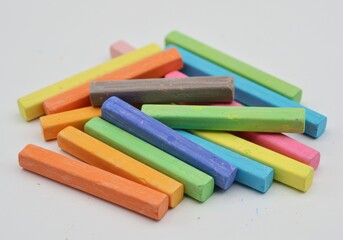 Fototapeta premium A colorful pile of chalk sticks lies scattered on a white surface, ready for art projects or classroom use