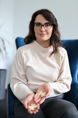 Obraz premium Young caucasian female holding puzzle pieces indoors on blue chair