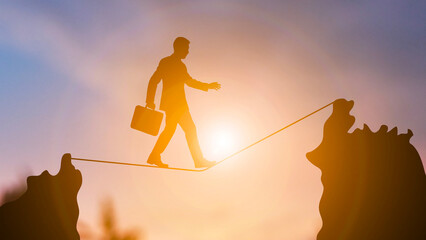 Businessman Walking on a Tightrope at Sunset