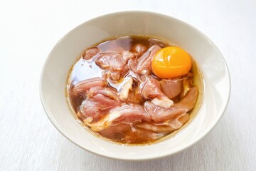 Marinated pork in white ceramic bowl on white background