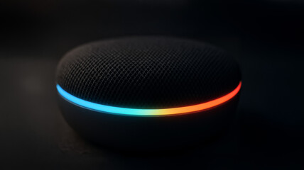 A modern AI voice assistant device glows with a rainbow LED ring in darkness, representing smart home technology and voice interaction.