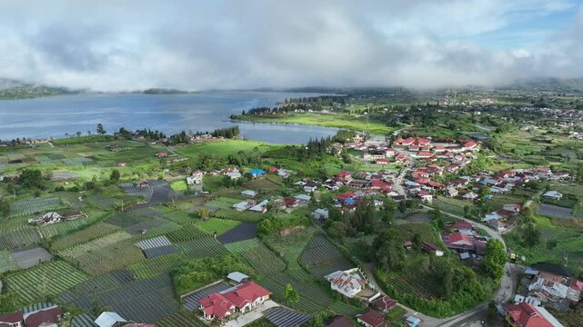 Aerial View of Lakeside Village with Lush Green Fields and Red Roof Houses