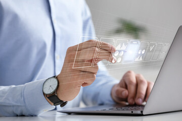 Man approving documents on virtual screen above laptop at table, closeup