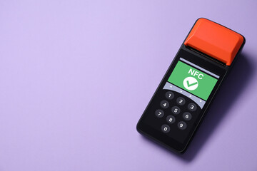 Obraz premium Payment terminal with NFC system on pale purple background, top view. Space for text