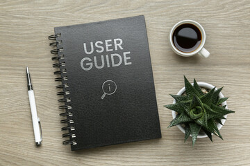 User Guide catalog, cup of coffee, pen and potted plant on wooden table, flat lay