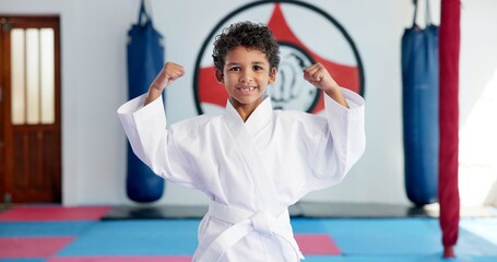 Bicep, karate and portrait of boy student in dojo for combat, martial arts or sports training. Exercise, fitness and flexing muscles with happy child in gym for education, development or growth © peopleimages.com