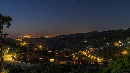 Obraz premium Night view of a mountain town with illuminated houses and streets under a starry sky