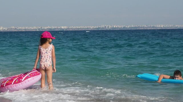 boy and girl swim on inflatable mattress and circle in the sea. playing in summer sunny day. Happy children kid enjoy and fun outdoor lifestyle travel ocean on beach holiday vacation. tropics sunbaths