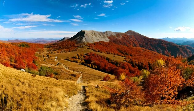 Vista panor&aacute;mica de una meseta &aacute;rida en la cima de una monta&ntilde;a con un camino cubierto de hierba por un colorido follaje oto&ntilde;al y &aacute;rboles rojos y verdes.