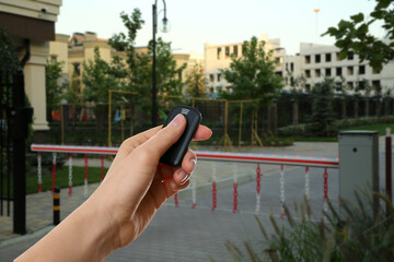 Woman using remote to control boom barrier outdoors, closeup