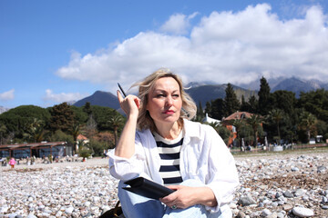 mature woman working outside in caffe on beach coast, lifestyle people concept