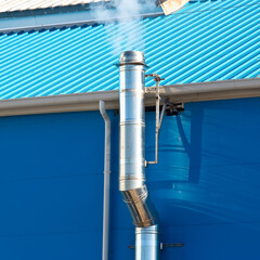 Metal chimney with stainless steel pipe with chimney pot blackened by smoke