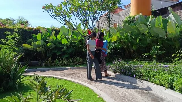 Two teenage girls pause during their walk to admire and pick purple Ruellia simplex flowers