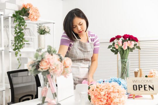 A couple of Asian entrepreneurs using their smartphones to sell flowers online.