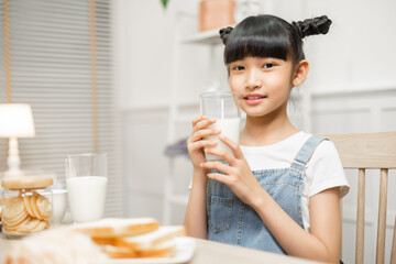 Asian family enjoying a nutritious breakfast at home, with their daughter holding a glass of milk.