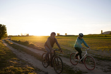 Obraz premium Senior couple cycling on country road at sunset