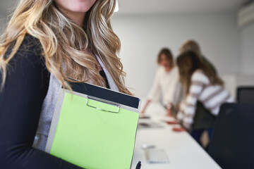 Unrecognizable Businesswoman holding clipboard with blurred team meeting in background