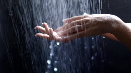Waterfall cascade: hands gracefully interacting under flowing water in slow motion