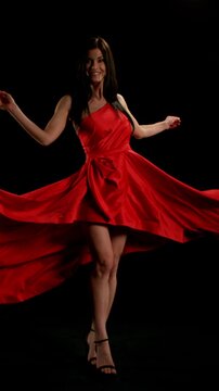 Brunette Woman in Ruby Red Dress Posing Against a Black Background . Filmed on High Speed Cinematic Camera in Super Slow Motion