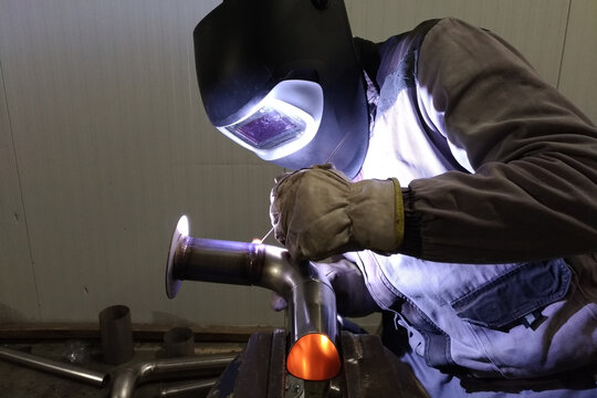 welder welds stainless steel pipe with tungsten electrode in protective gas environment