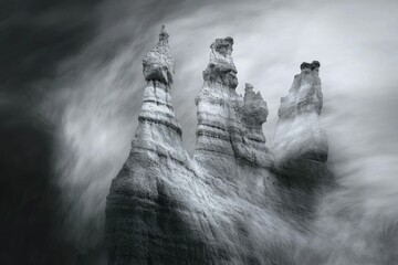 Three towering rock formations stand against a dramatic, motion-blurred sky, creating a surreal and powerful image.