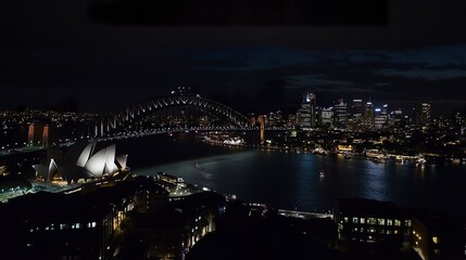 A spectacular night view of the Harbour Bridge, its lights complementing Sydney's glittering skyline, with gentle reflections stretching across the harbor. 