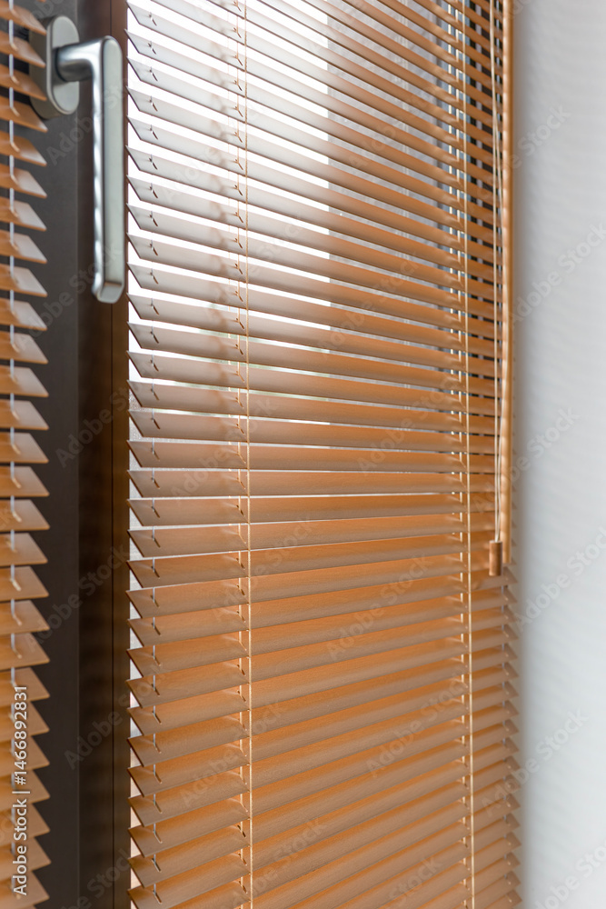 Poster wooden blinds close-up partially closed on a window, with sunlight filtering through the horizontal 