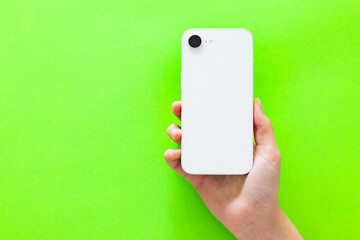 Back of mobile phone in hand on green background