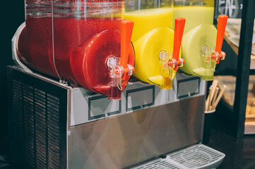 Close-up of three slushy machines with red and yellow flavors.