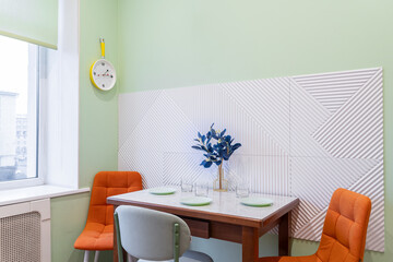 simple kitchen design. There are plates and flowers on the kitchen table, chairs near the table....