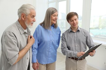 Smiling real estate agent with clipboard working with couple at home
