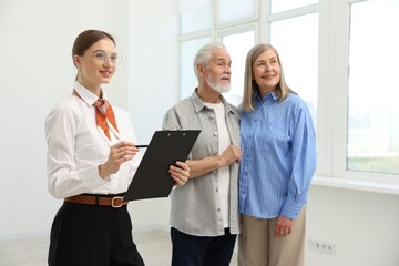 Smiling real estate agent with clipboard and couple at home