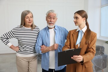 Real estate agent with clipboard working with couple at home