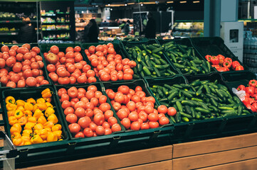 Fresh tomatoes and cucumbers on display in supermarket.
