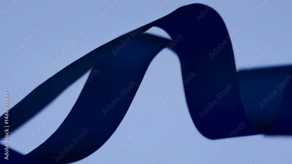 Aufkleber dark blue ribbon curves and bends against a pale blue background creating smooth lines and interesti