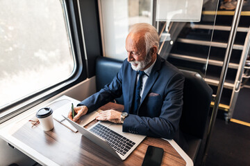 Senior Businessman Working on Laptop During Train Journey