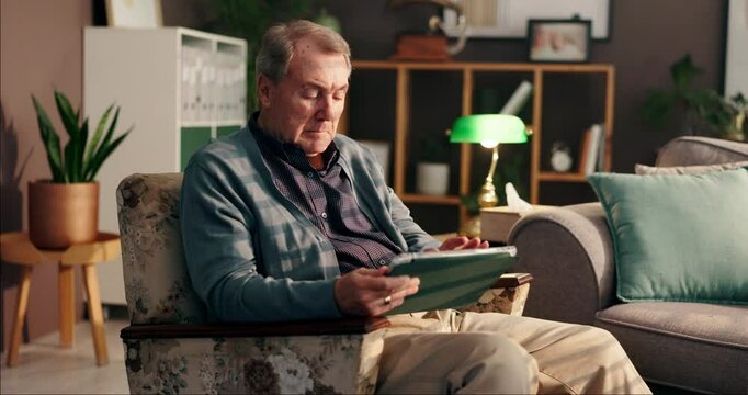 Elderly man, tablet and relax on sofa with media, digital album and new memory aid app. Senior person, tech and scroll in home for learning software, connectivity and interacting with online puzzle